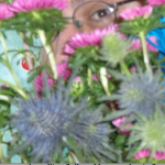 a brown eye with glasses visible through flowers